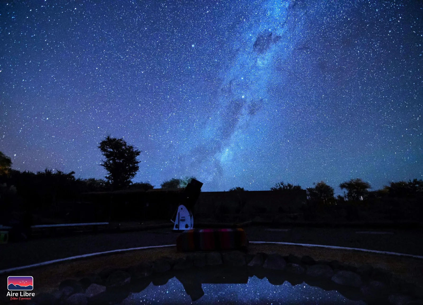 The Milky Way rises over the observation site, its stars mirrored in the circular water pool in the foreground